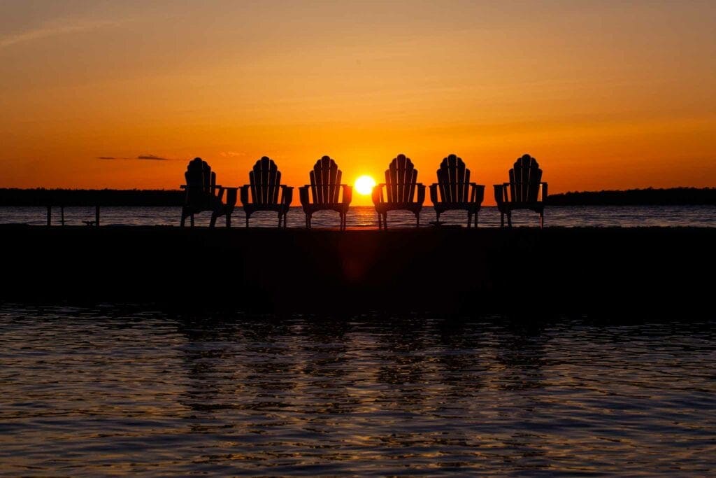 Six deck chairs silhouetted on the Edgewater pier against a blazing Ephraim sunset