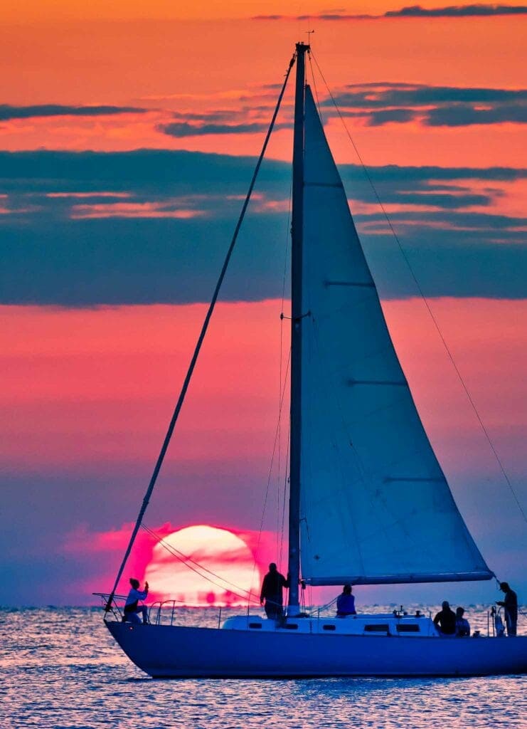 A sailboat silhouetted against a glowing orange sunset off Sister Bay