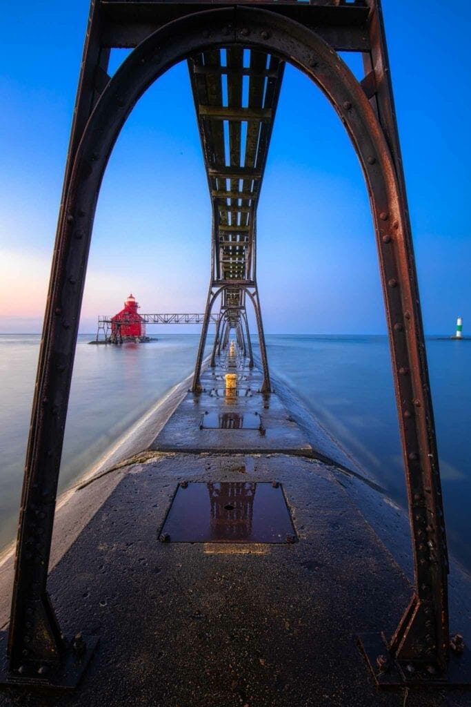 The red Sturgeon Bay pierhead light at the end of the catwalk, reflected in the wet pier at dawn