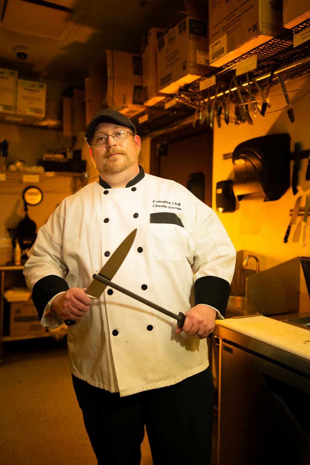A chef portrait in warm light in his restaurant kitchen