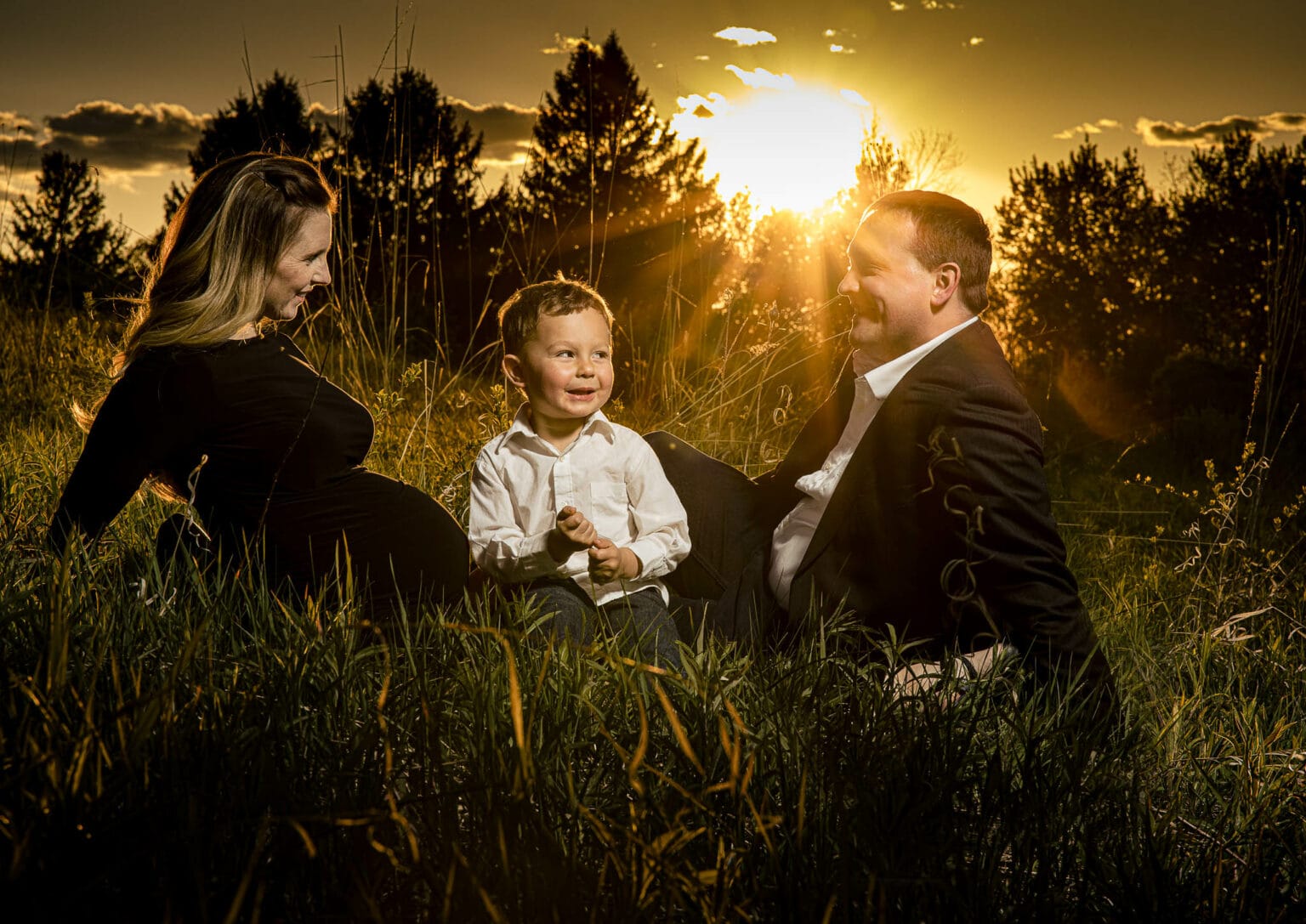 Family of three in golden sunset light among tall grasses