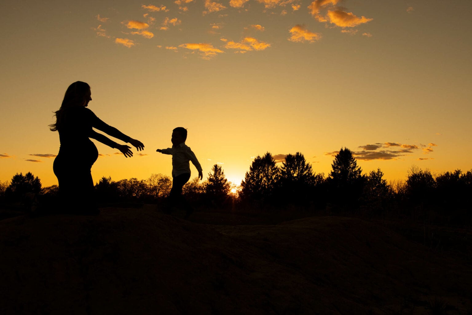 Silhouetted mother and child against a sunset sky