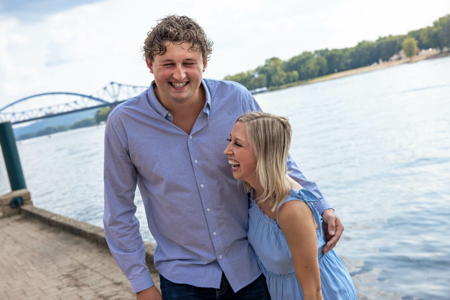 An engaged couple laughing on the river walk at Riverside Park, La Crosse