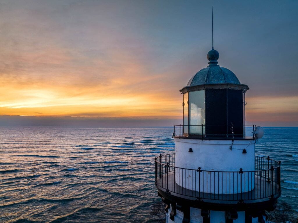 The white Cana Island lighthouse and its copper lantern at sunrise over Lake Michigan