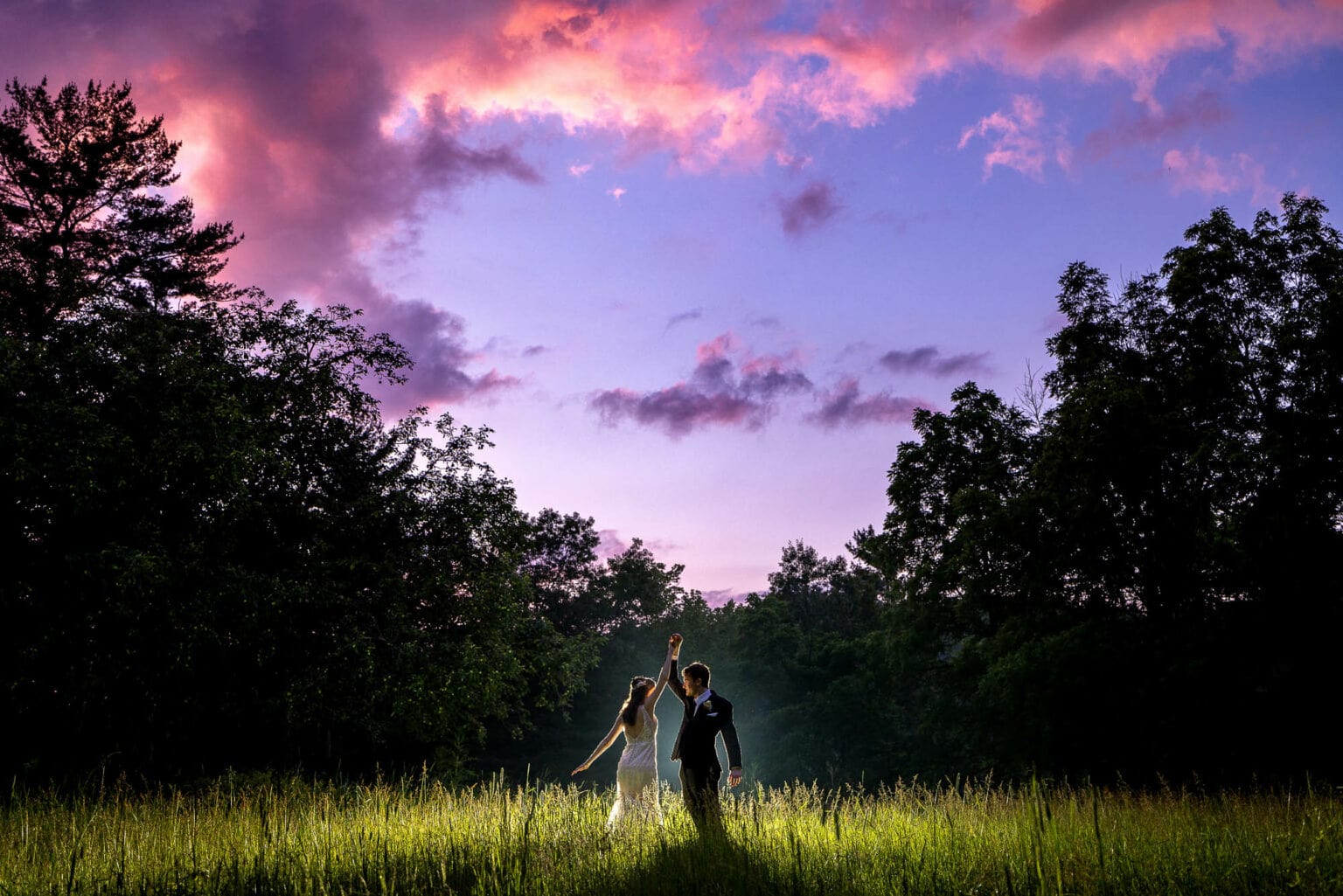 Bride and groom in a meadow under a pink sky at Winnebago Springs, Caledonia, Minnesota