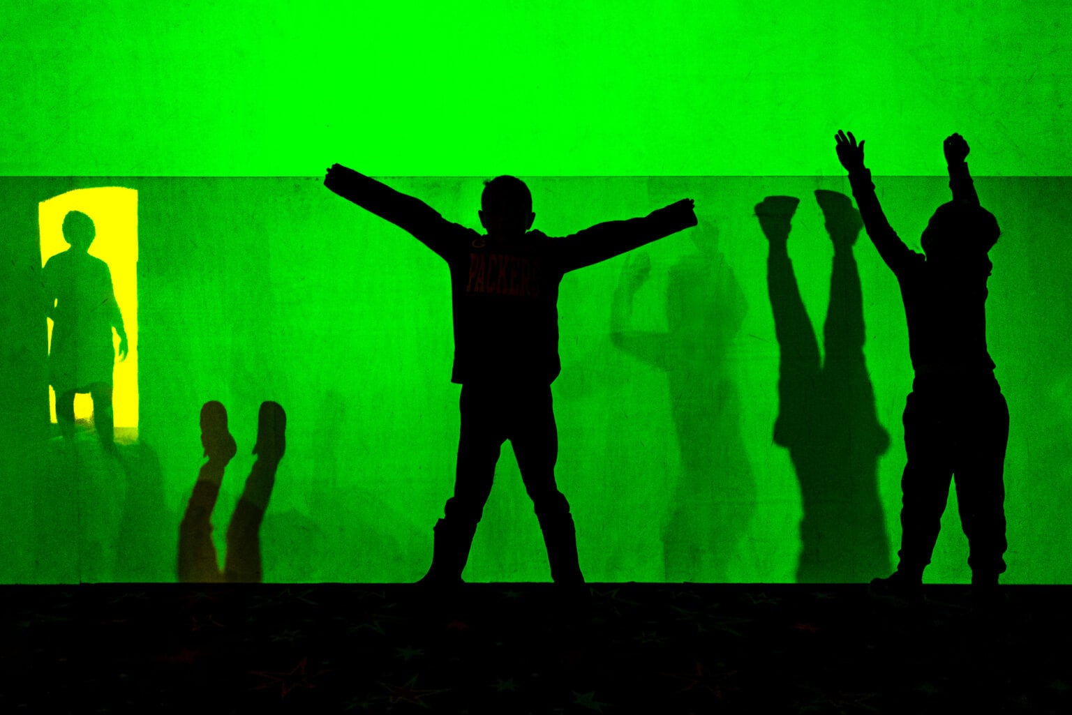 Children celebrating in silhouette, green museum light