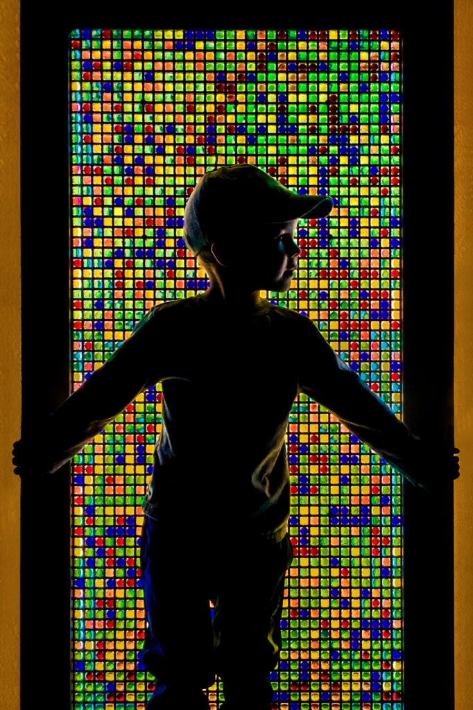Silhouetted figure with arms outstretched facing a vibrant grid of colorful illuminated squares