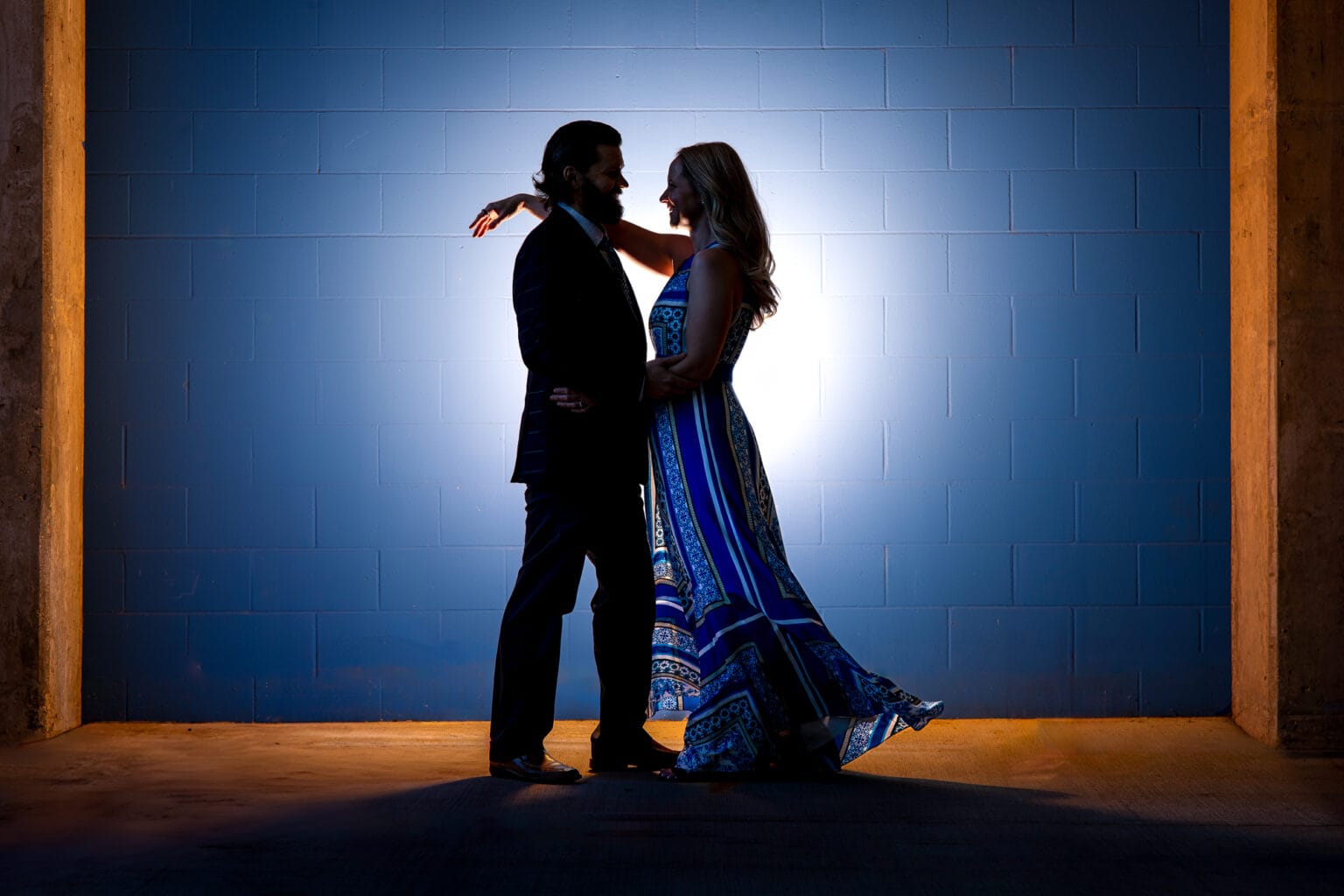 Engaged couple silhouetted against a glowing blue backdrop