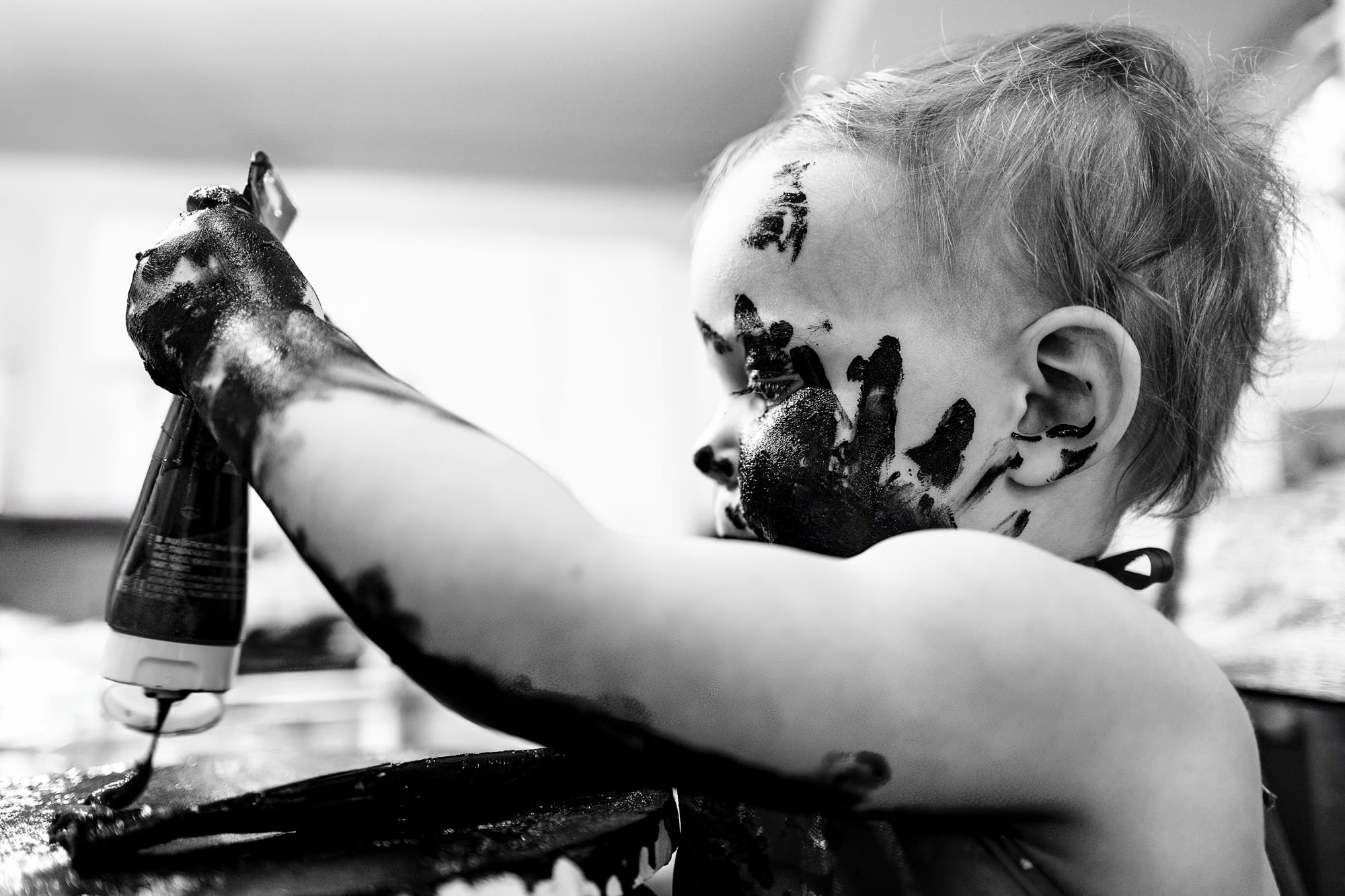 A toddler covered in paint, mid-mess