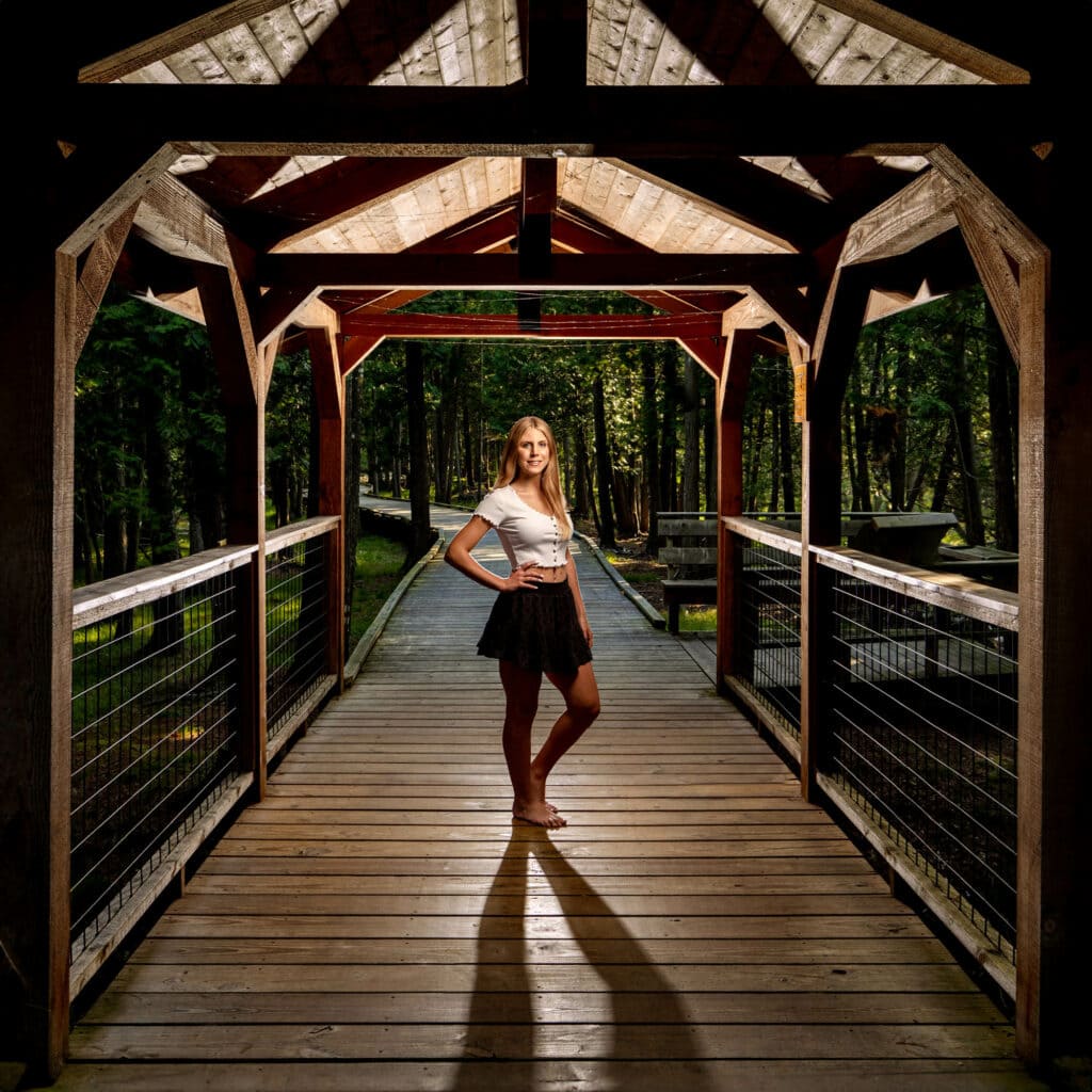 Kaitlyn on a covered wooden bridge in a forest under built light