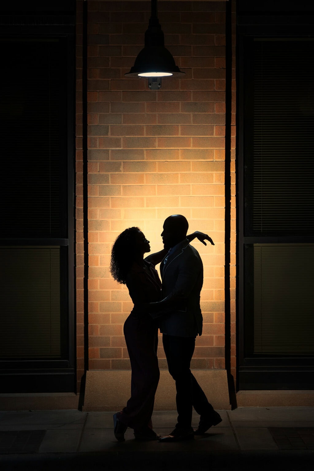 A couple silhouetted under a single light in a downtown La Crosse alley