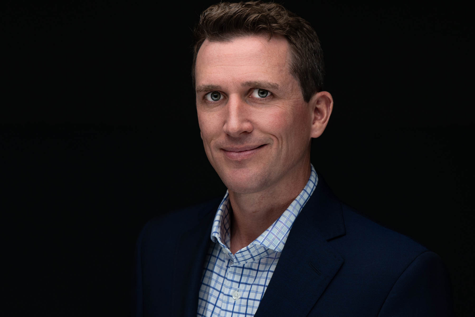 Headshot of a man in a navy blazer and light blue shirt