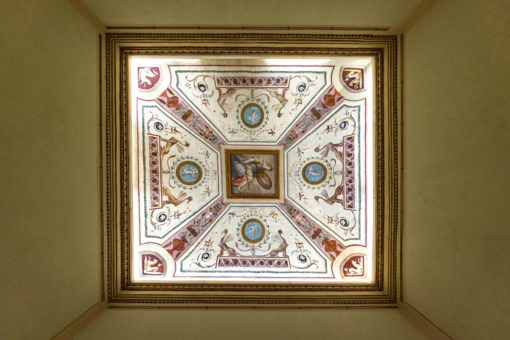 Ornate Renaissance ceiling with geometric panels, frescoed medallions, and gilt architectural details in Florence, Italy