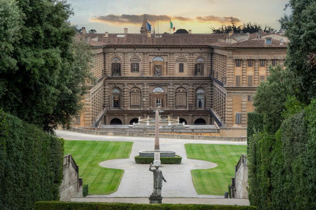 A Renaissance courtyard framed by cypress trees at Palazzo Pitti, golden sunset light on the stone