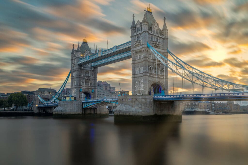 Tower Bridge lit gold at sunset, reflected in the calm River Thames, London