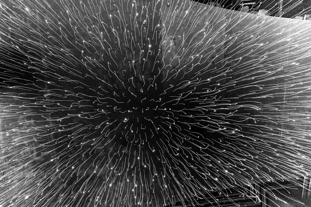 Black and white radiating lines burst outward from a dark center, creating an abstract starburst pattern with dramatic motion and depth