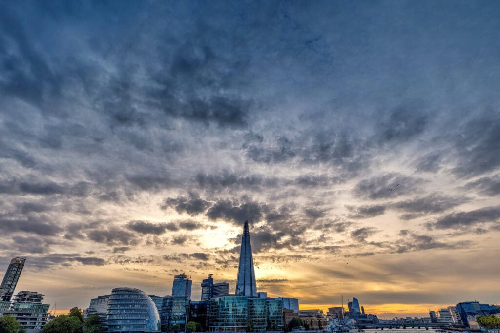 Dramatic sunset over London's skyline with The Shard silhouetted against golden and stormy clouds
