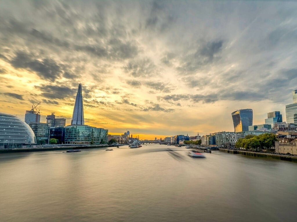 London skyline at sunset with The Shard and Thames River, golden hour clouds reflecting on water