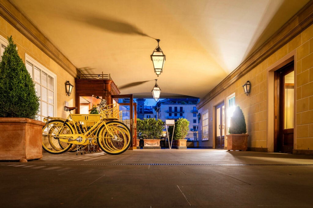 A yellow vintage bike parked under an arched colonnade at dusk, Florence