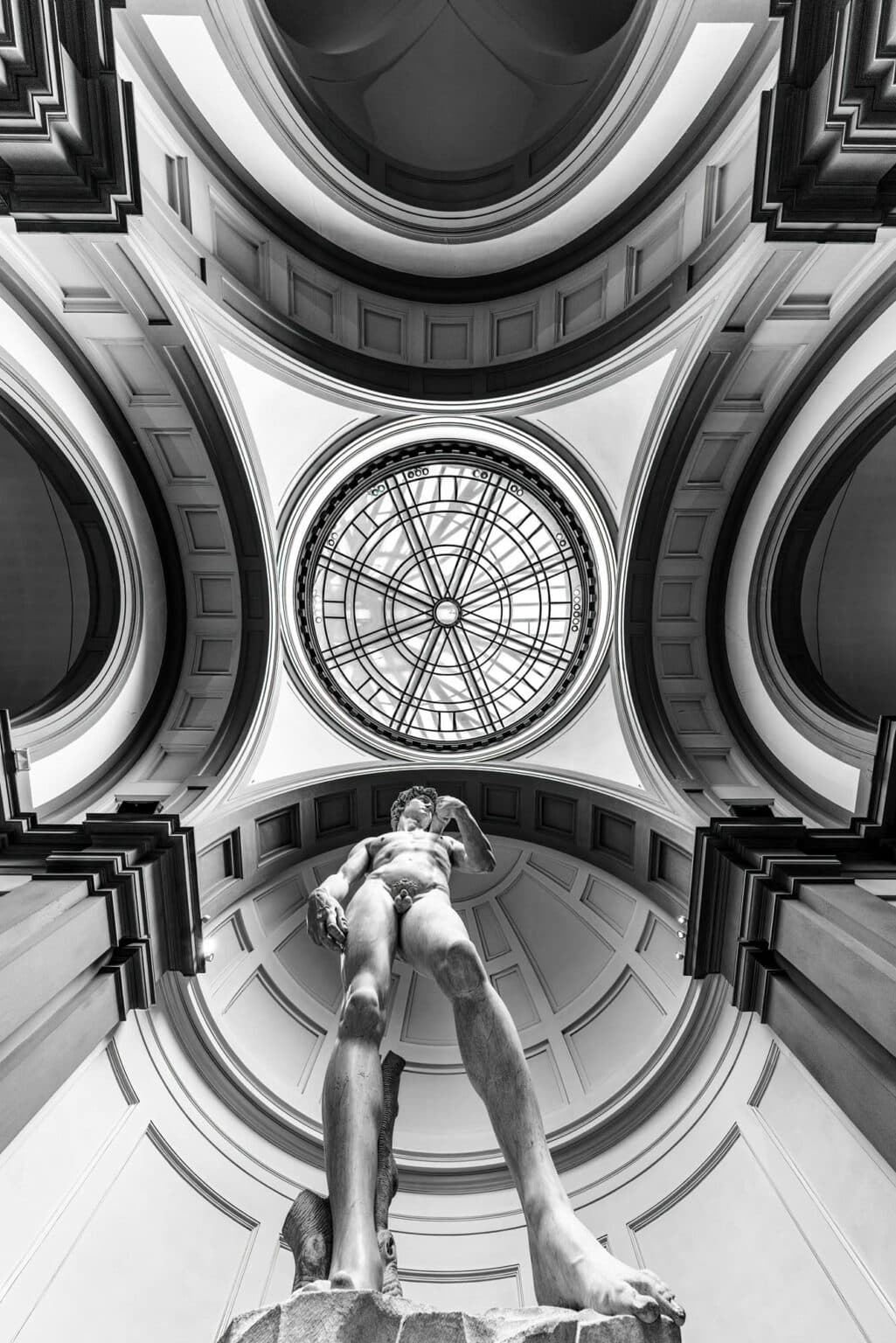 Statue reaching upward toward ornate circular skylight and vaulted architecture, London, England