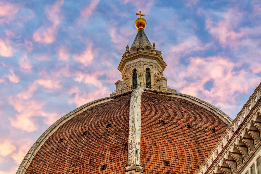 The Duomo's dome against a sky streaked pink and gold at sunset