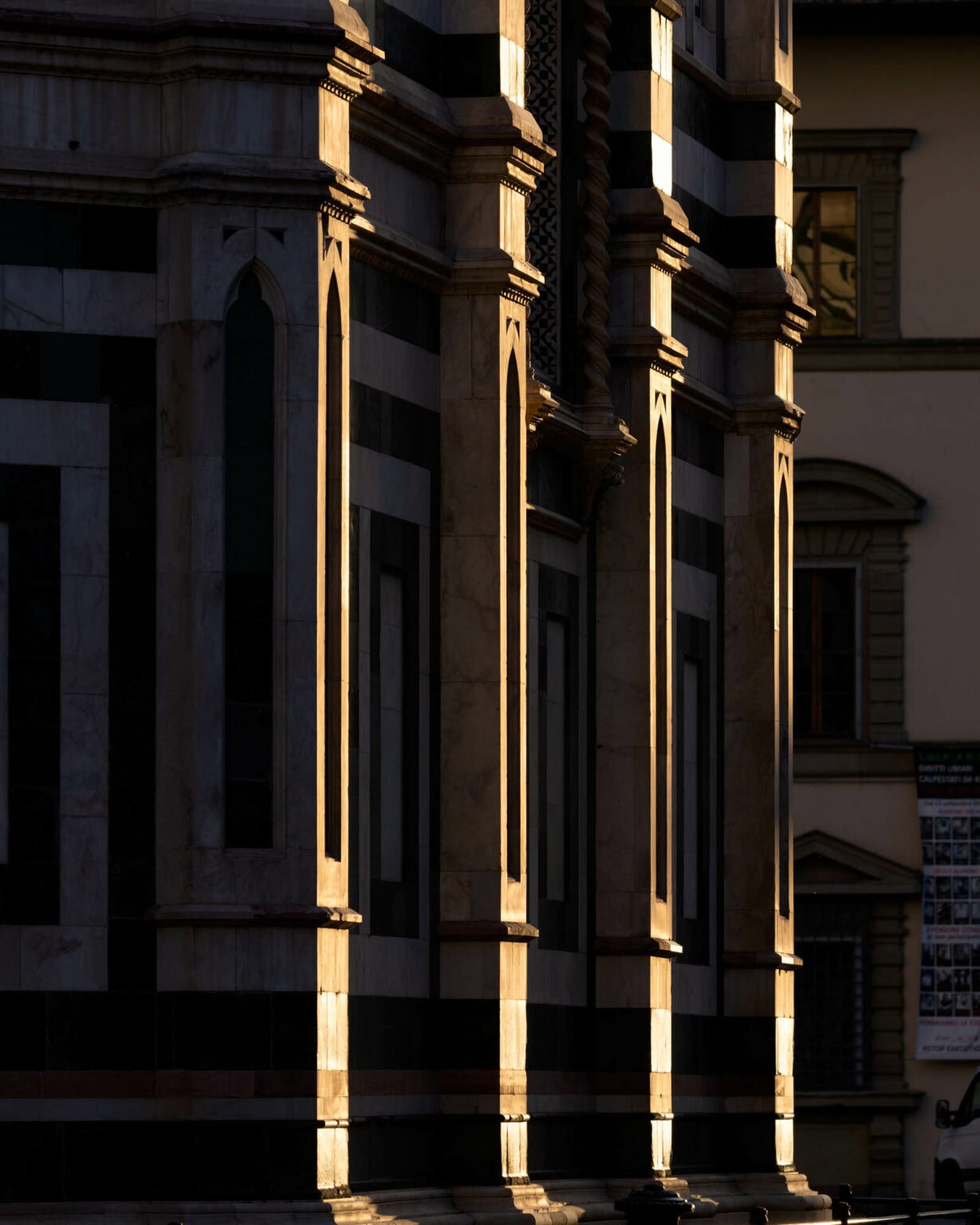 Golden afternoon light illuminates classical stone columns and arches of a historic European building facade