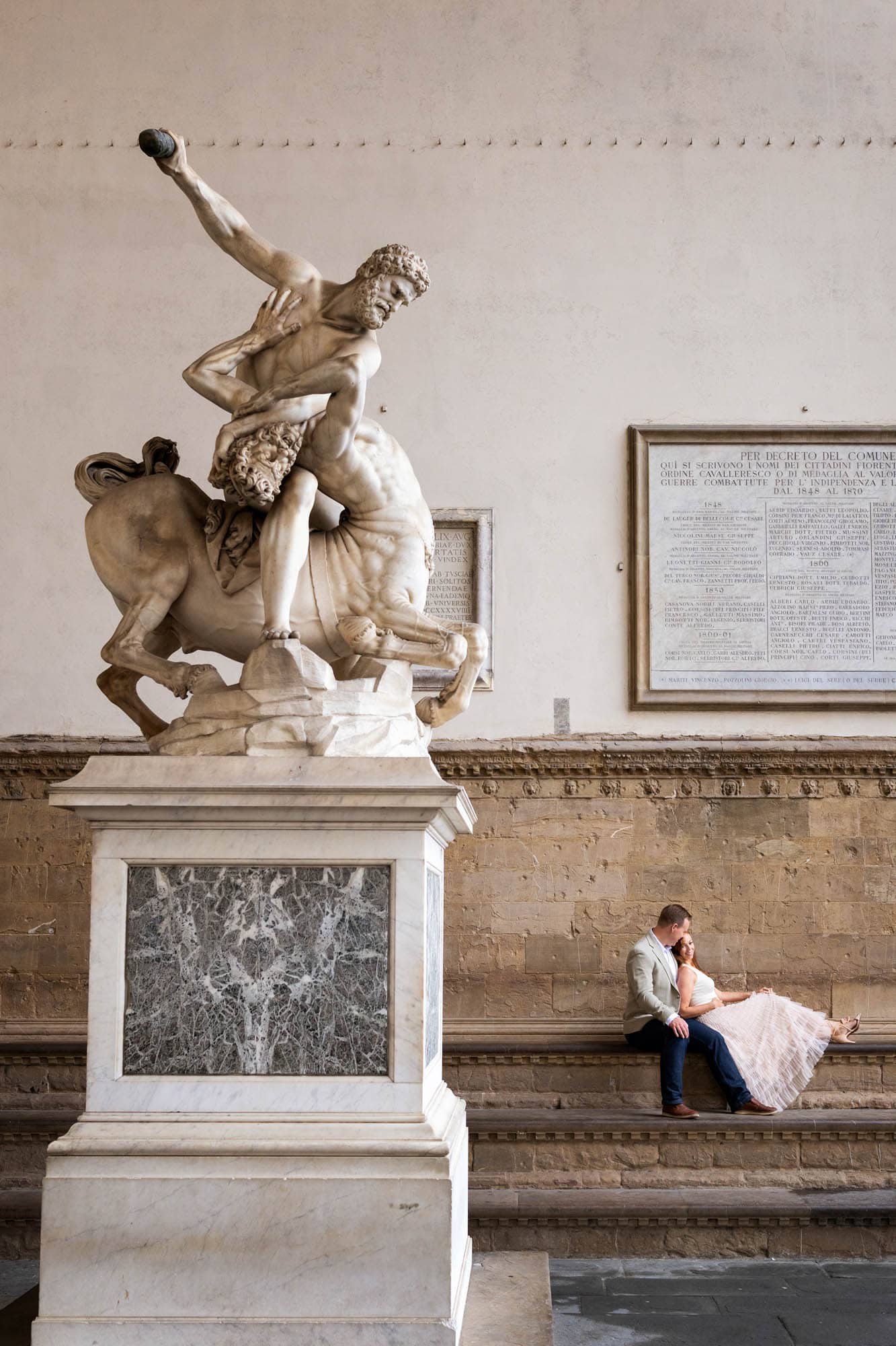 Jeff and Alisha Wiswell sitting beneath a Renaissance statue in Florence
