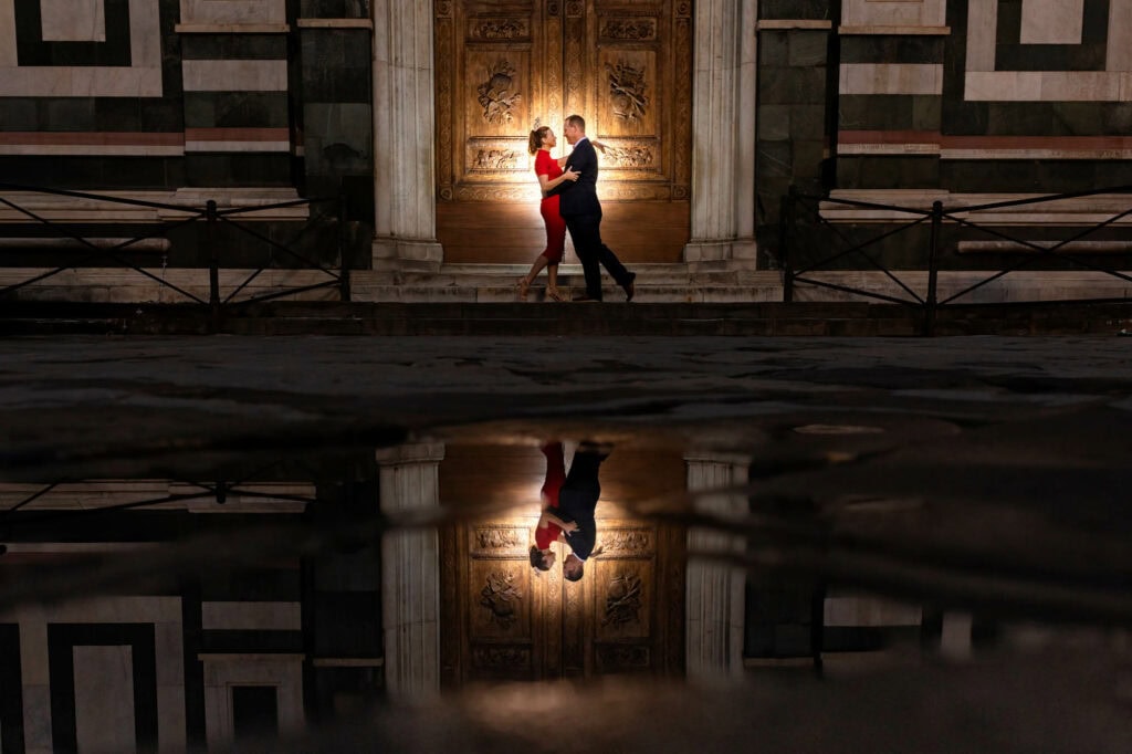 Jeff and Alisha Wiswell reflected in a puddle outside the Florence Baptistery at night. Photo by Fabio Mirulla.
