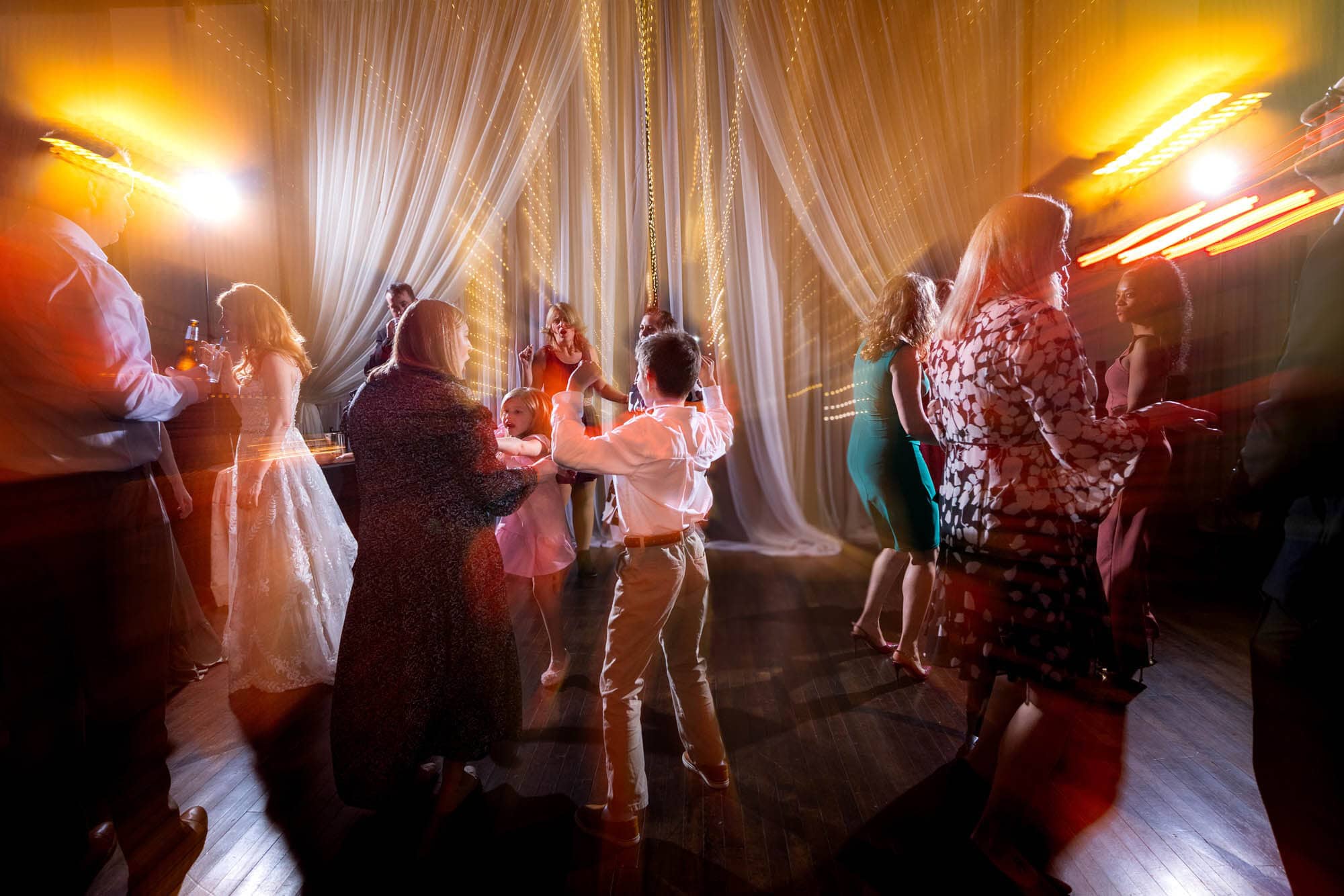 Wedding guests dancing together under string lights