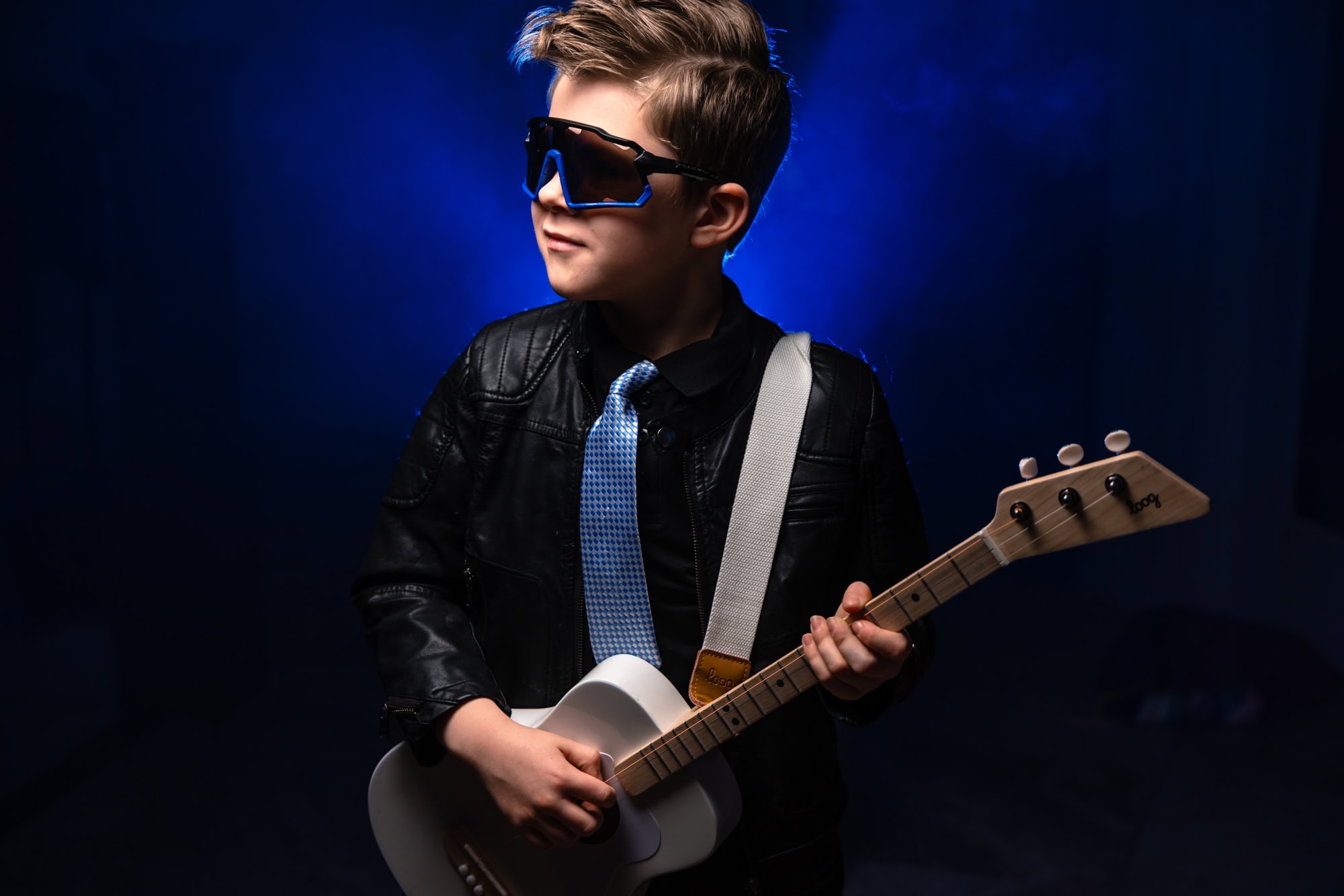 Young musician in a leather jacket playing acoustic guitar