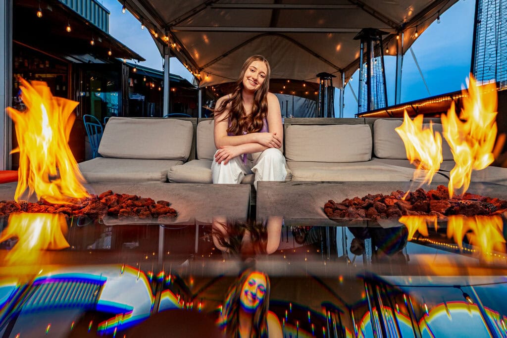 Natalia between two fire tables on a rooftop lounge, downtown La Crosse