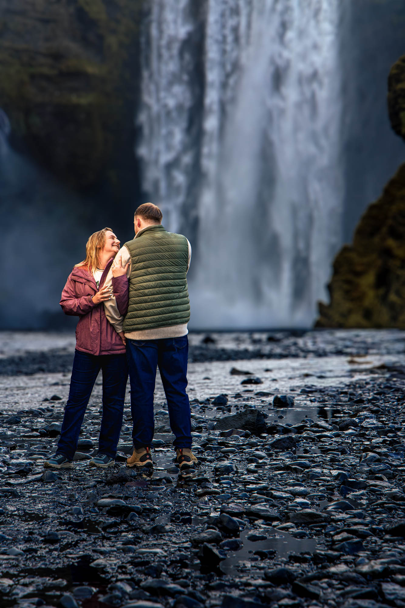 A couple together at the foot of a waterfall in Iceland