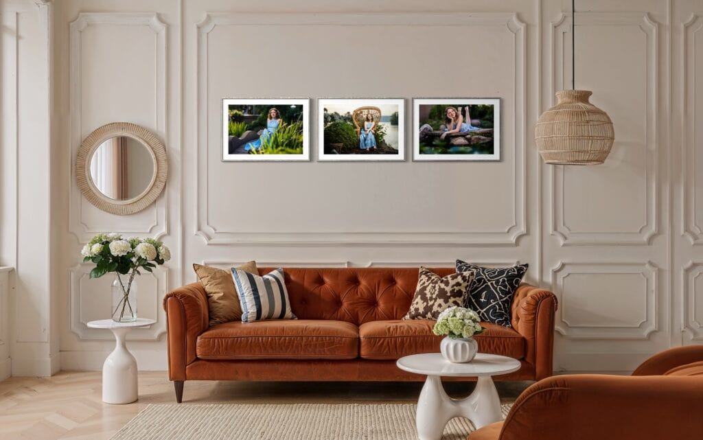 Styled living room with rust-colored Chesterfield sofa, white paneling, framed portrait photography above, and natural light from left