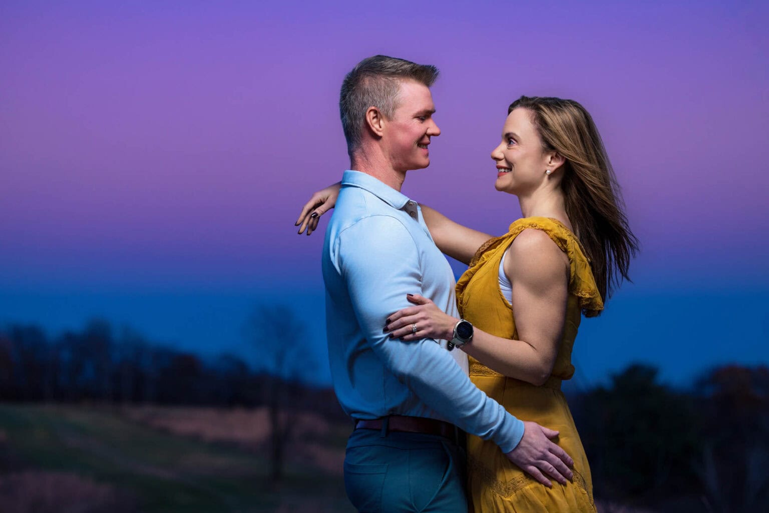 Engaged couple at twilight, purple sky behind