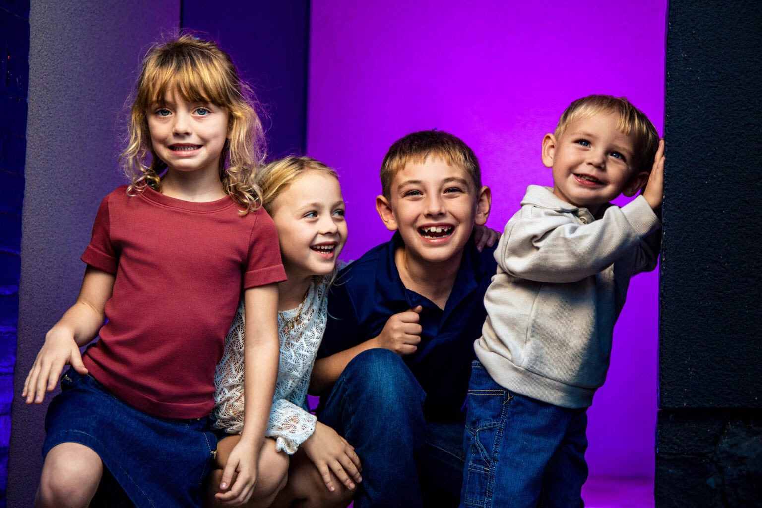 Four children against vibrant purple studio lighting