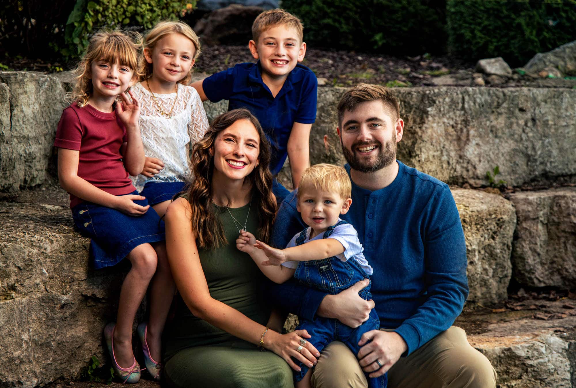 Family of six together on the garden steps, kids leaning in playfully