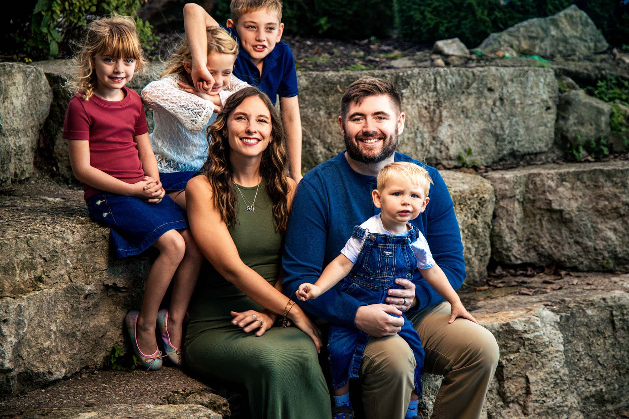 Family of six smiling together on wide stone garden steps