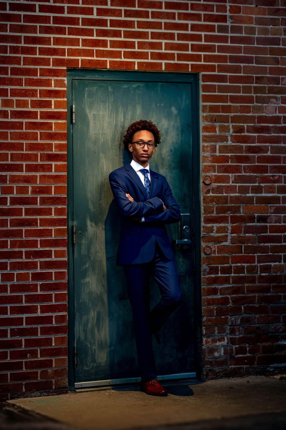 Kaleb beside a green door in a downtown La Crosse alley