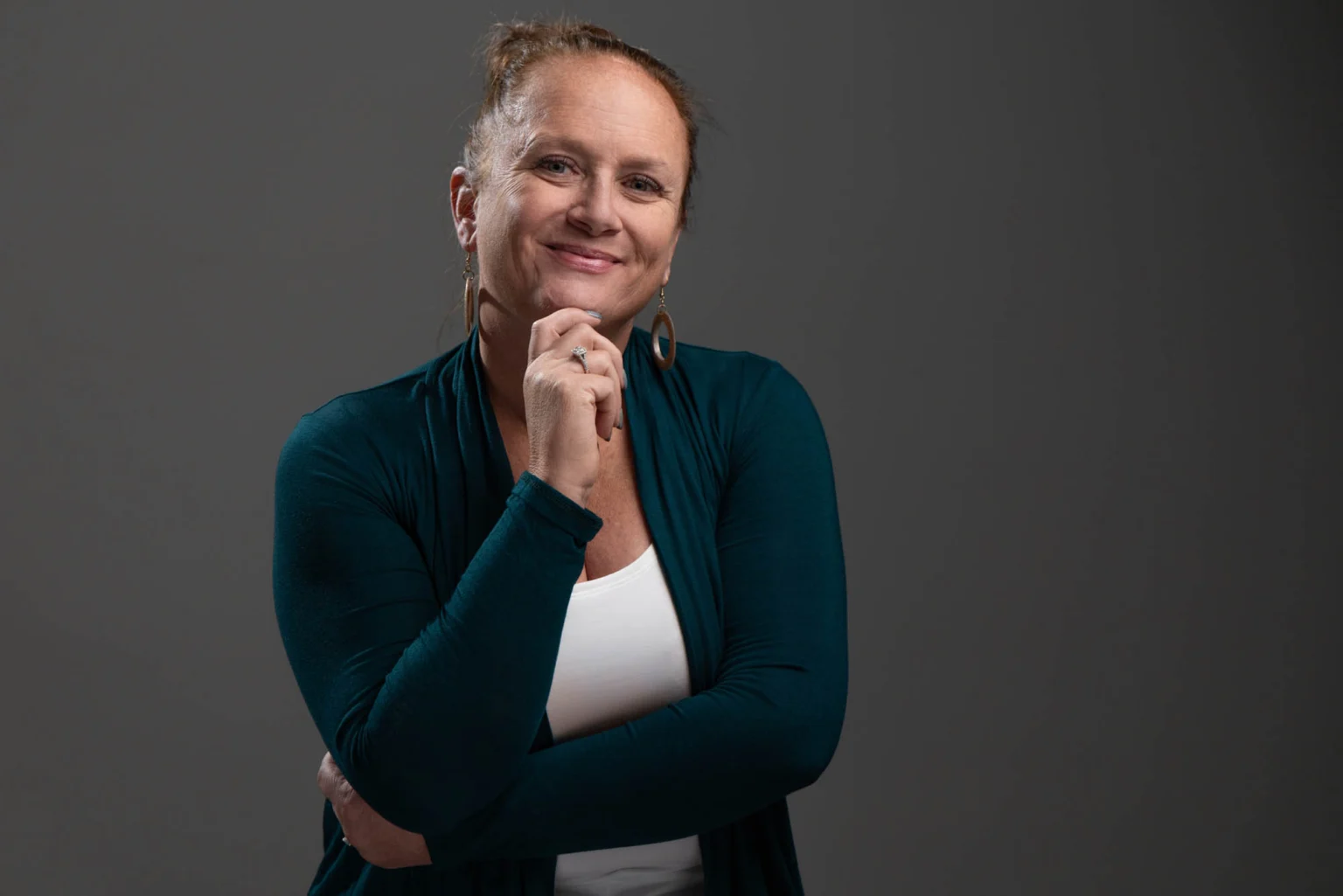 Studio portrait of a woman in a teal cardigan against a grey background