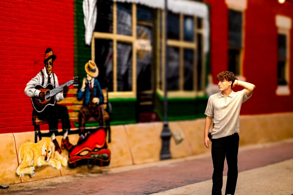 High school senior looking confidently off-camera beside a musician mural in downtown La Crosse, Wisconsin