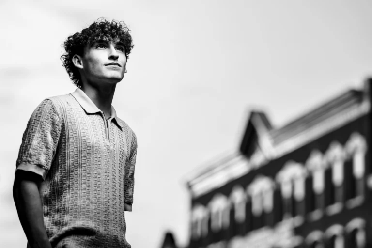Dramatic black and white low-angle portrait gazing upward beside a historic brick building in downtown La Crosse, Wisconsin.