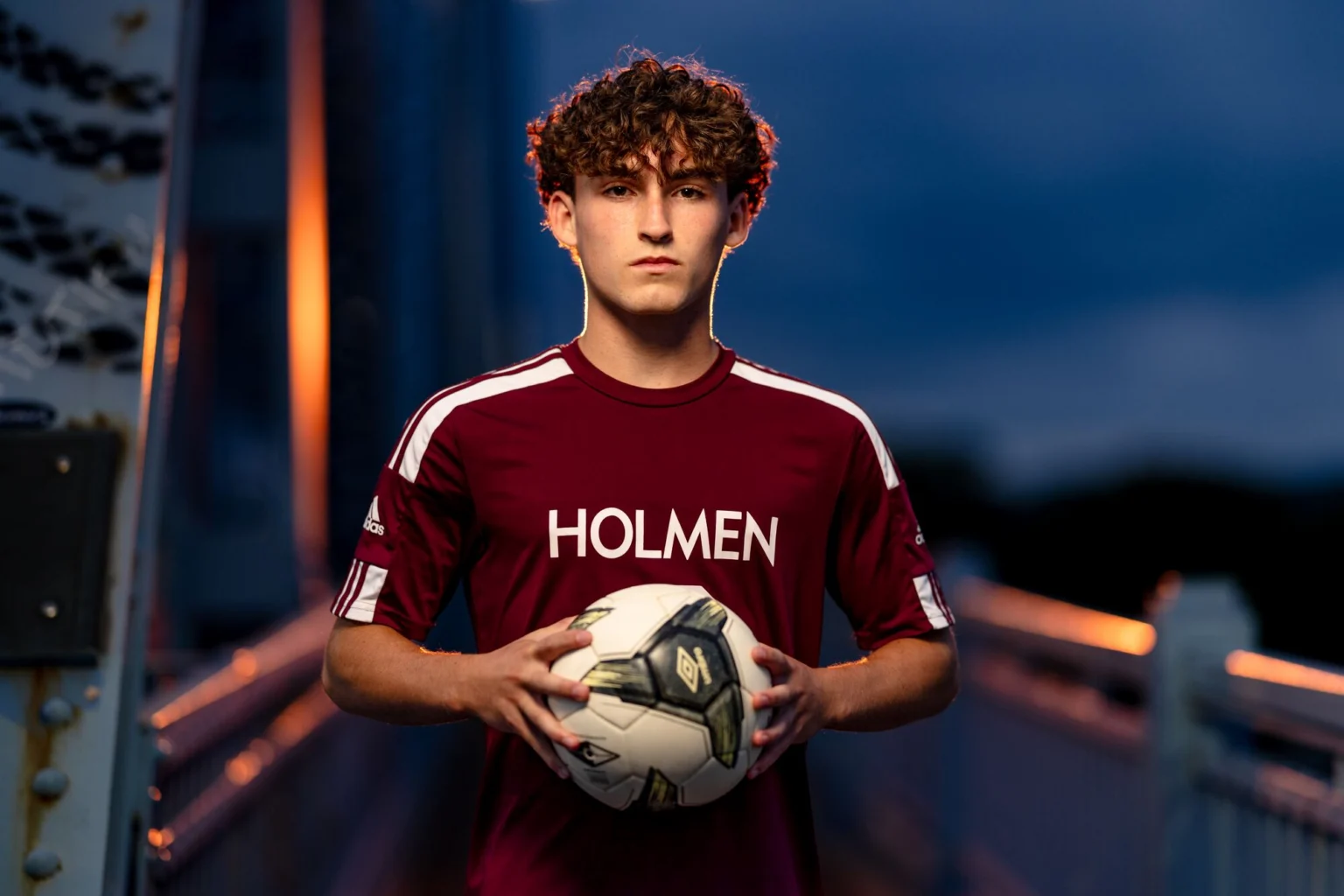 Deacon holding a soccer ball on the Cass Street Bridge at dusk