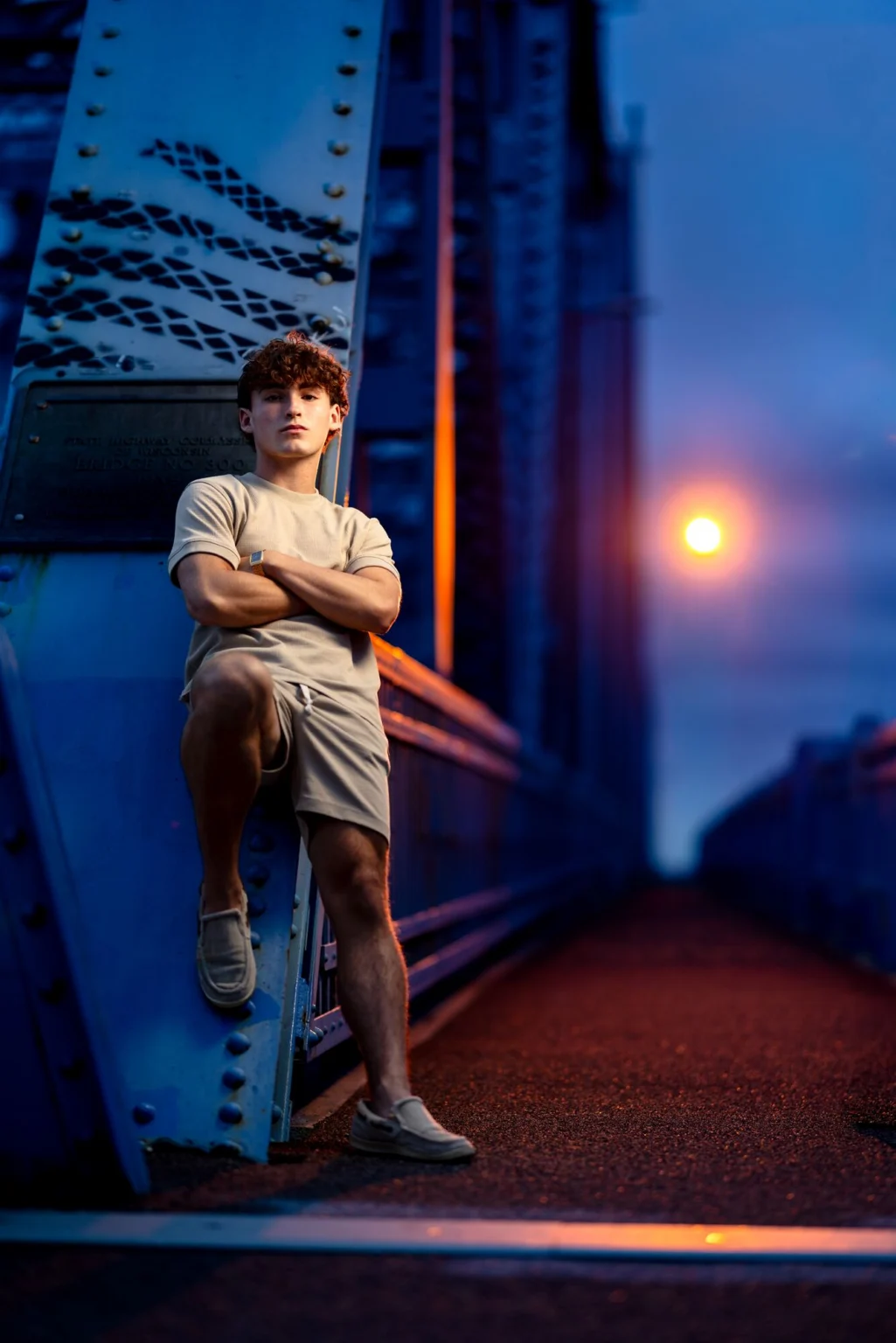Deacon on the Cass Street Bridge at blue hour, arms crossed under the bridge lamp