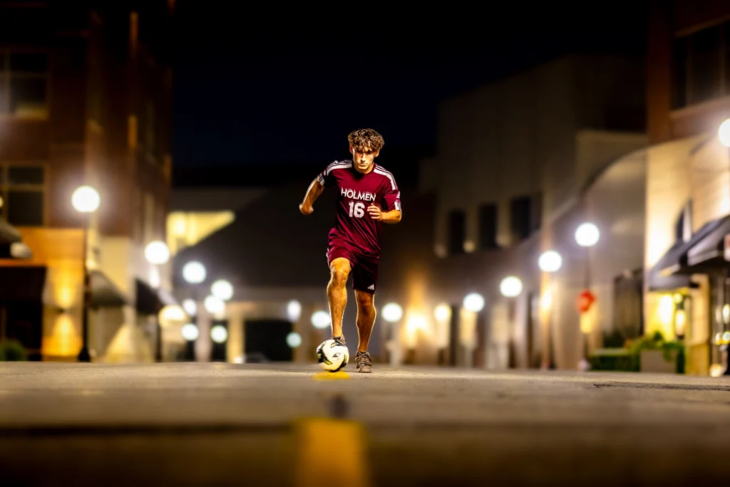 Deacon with a soccer ball on a lamplit downtown La Crosse street at night