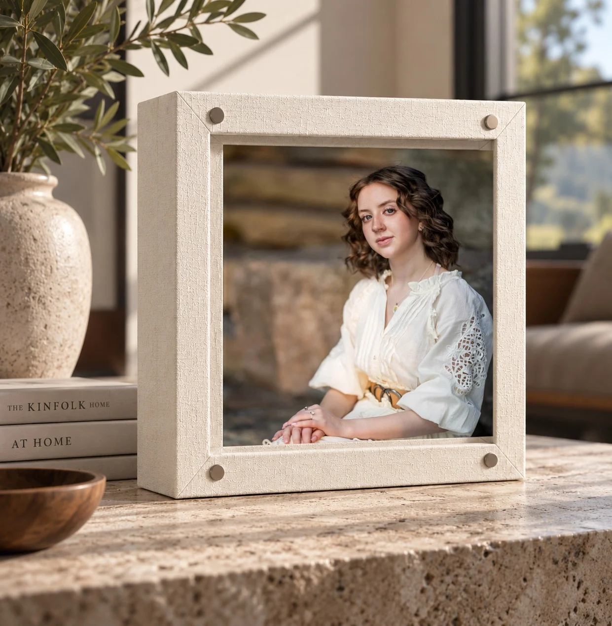 A cream GoBook album with a senior portrait on the cover, on a travertine table