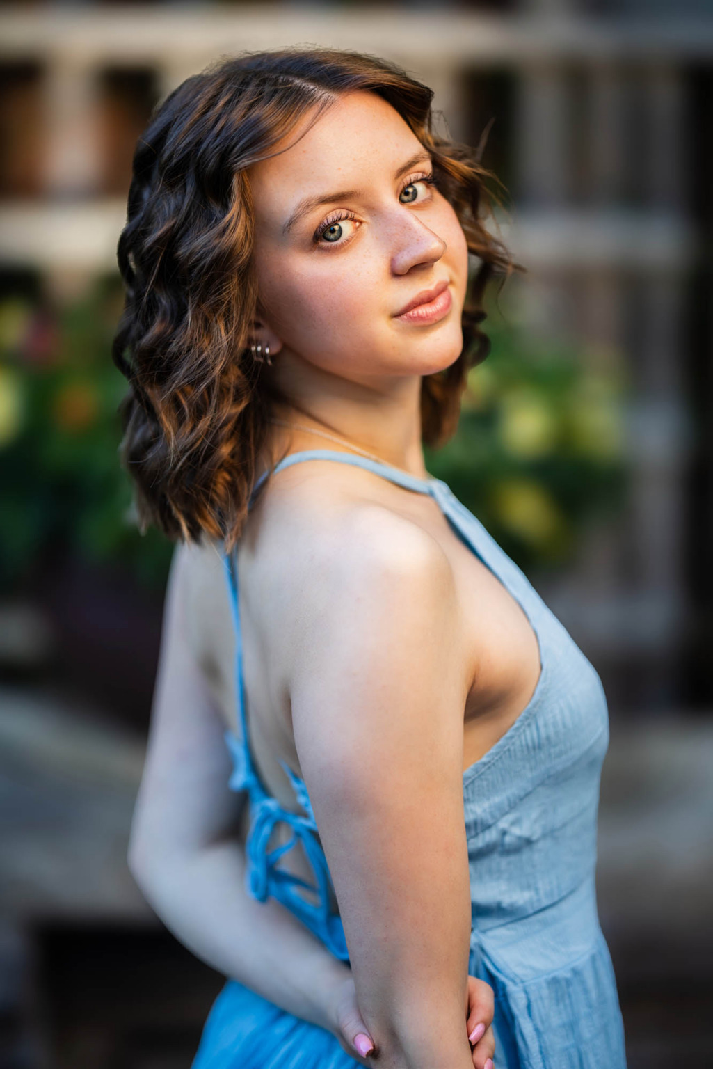 High school senior in a blue sundress glancing over her shoulder