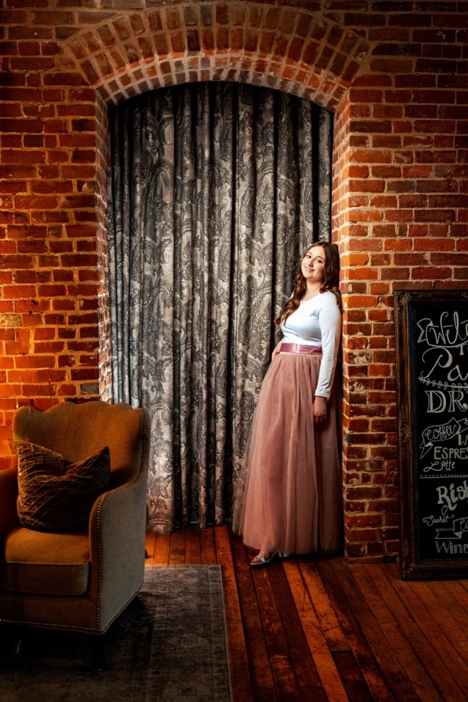 High school senior girl in a tulle skirt against an arched brick wall