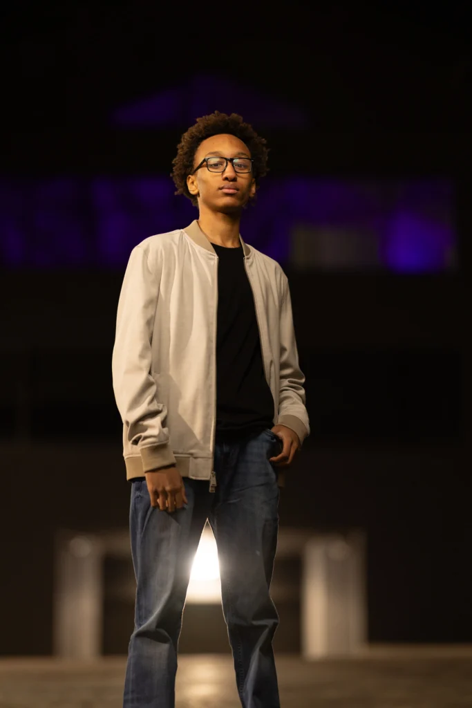High school senior in a bomber jacket under dramatic flash at night