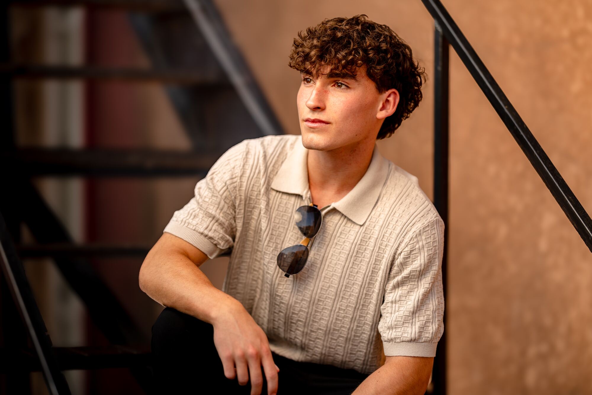Cream knit polo, sunglasses, urban metal staircase. La Crosse senior portrait.