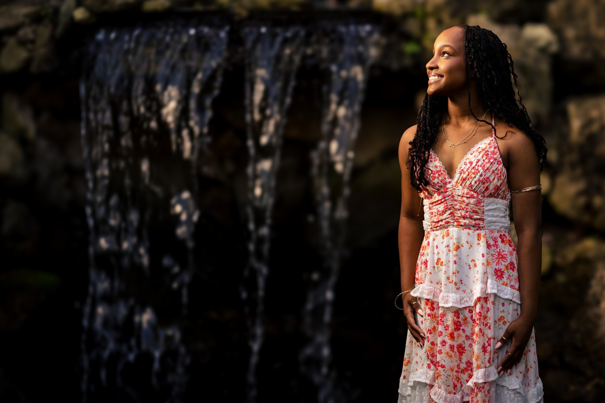 Senior girl in a floral dress smiling beside the waterfall at Riverside International Friendship Gardens, La Crosse WI, by J.L. Wiswell Photography
